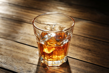 Glass of whisky on wooden table closeup
