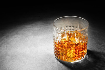 Glass of whisky on grey textured table closeup