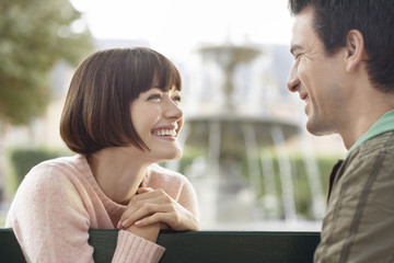 Closeup side view of a young couple smiling on park bench