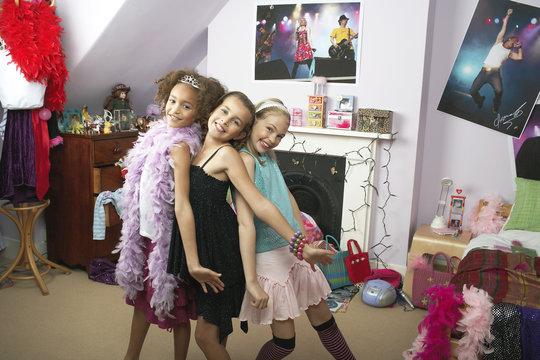 Happy Young Girls Striking A Pose In Trendy Bedroom At Slumber Party