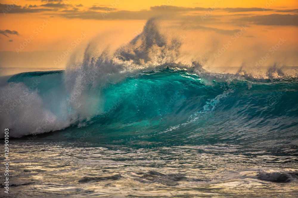 Wall mural green blue ocean splashing wave in front of orange sunset sky background