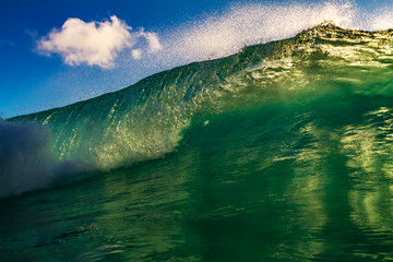 Emerald green blue golden sunset front view of ocean wave