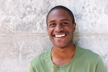 Fototapeta premium cheerful young black man smiling against wall