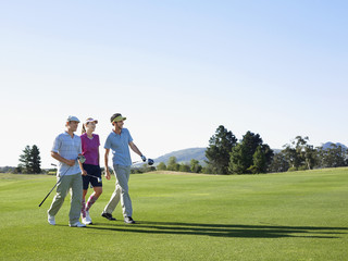 Three young golfers walking on golf course
