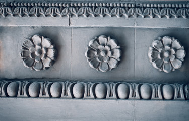 Old antique plaster ceiling plate or rose in an old victorian house. Ancient stucco ceiling texture. Wall ornament, architecture detail. A detail of a building facade decor.