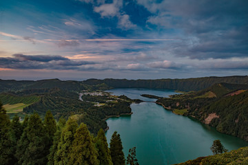 Obraz premium Mountain landscape in green valley with green lake in Azores island mountains with beautiful clouds at sunset time