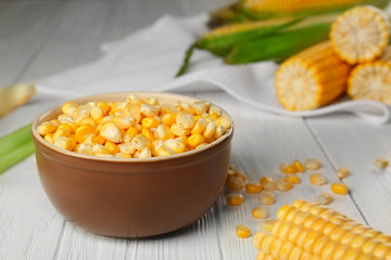 Bowl with corn seeds on wooden rustic table, closeup