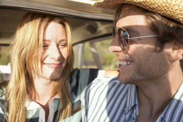 Young couple smiling while looking at each other during road trip