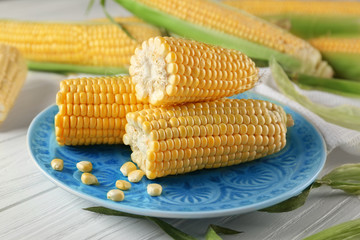 Plate with corncobs and seeds on wooden table