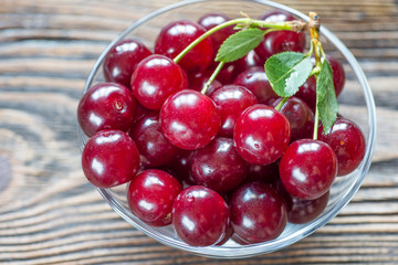 Cherries in glass bowl on wooden background