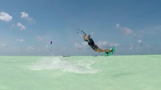 SLOW MOTION: Young kiter woman kiteboard jumping in beautiful Zanzibar lagoon