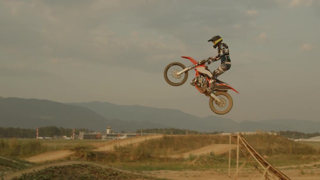 SLOW MOTION: Professional biker jumps big air trick at dusty motocross circuit