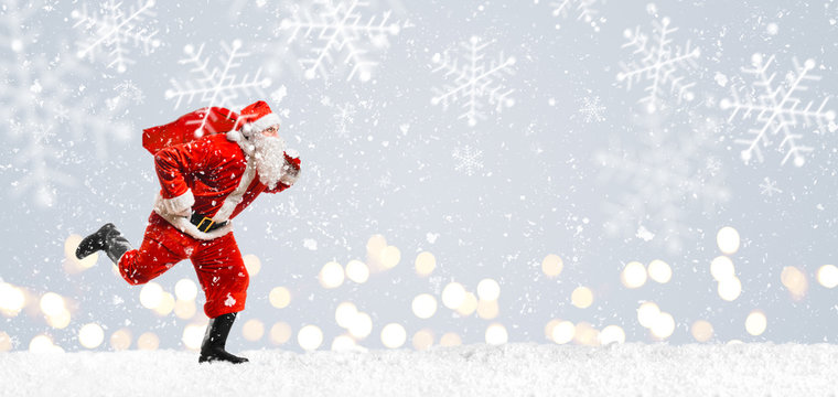 Santa Claus Running At New Year Or Christmas Delivery Rush With Gift Bag Full Of Presents On Snow