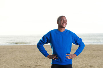 handsome african guy standing at the beach in blue sweatshirt