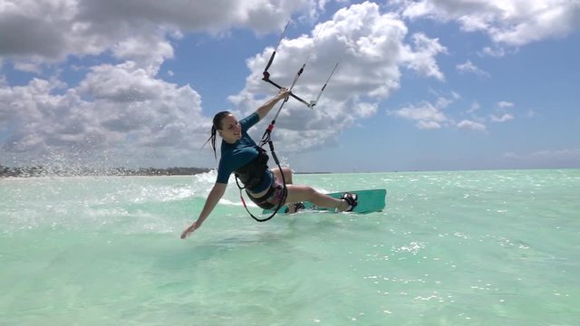 SLOW MOTION: Young surfer girl kiteboarding and doing hand drag splashing water