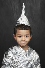 Portrait of a young boy in aluminum foil knight costume against black background