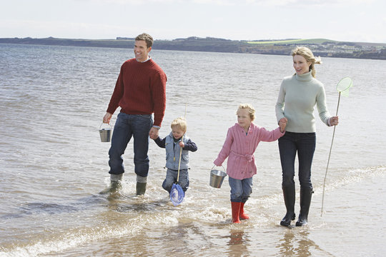Happy parents with two children enjoying vacation on beach