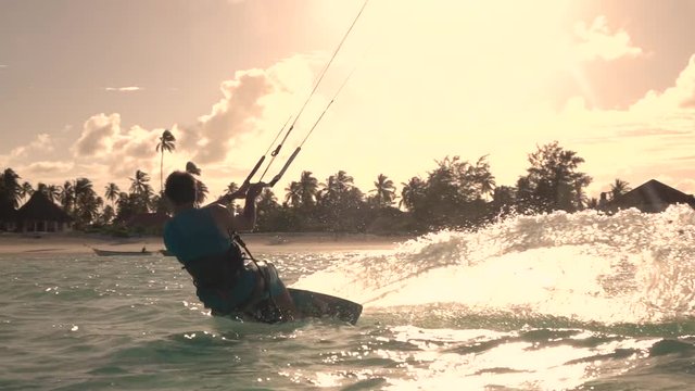 SLOW MOTION: Extreme surfer kiteboarding and jumping high at summer sunset