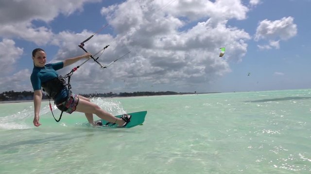 SLOW MOTION: Cheerful surfer girl has fun kitesurfing in amazing emerald ocean