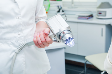 Doctor is holding a modern medical equipment for face skin treatment, close up