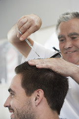 Closeup of happy man getting an haircut from barber in hair salon