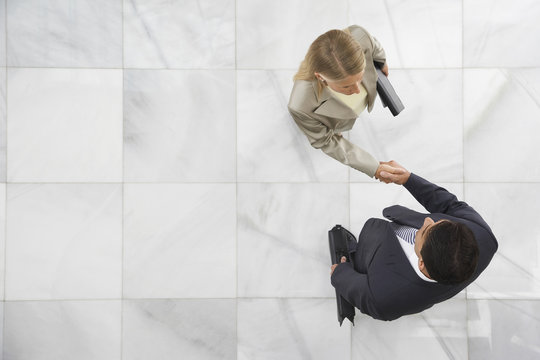 Top View Of A Businessman And Woman Shaking Hands In Office Lobby