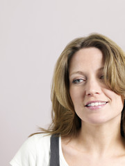 Naklejka premium Closeup of beautiful woman looking away and smiling on colored background