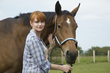 Obraz premium Portrait of a beautiful young woman with horse in field