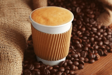 Cup of coffee with roasted beans on wooden table closeup