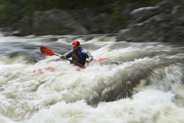 Fototapeta na wymiar View of a young man kayaking in rough river