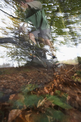 Blurred motion of man riding mountain bike through forest