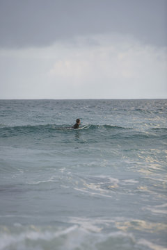 Surfer sitting on surfboard in sea side view