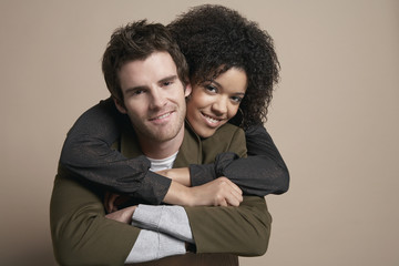 Portrait of loving young couple smiling on colored background