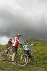 Naklejka premium Low angle view of three cyclists against the hill