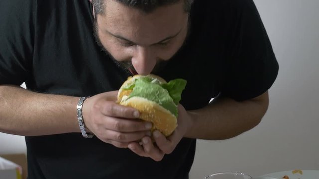 man eating with voracity an XXL hamburger: diet, overweight, obesity, junk food