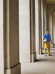 Full length portrait of a soccer player holding ball in portico