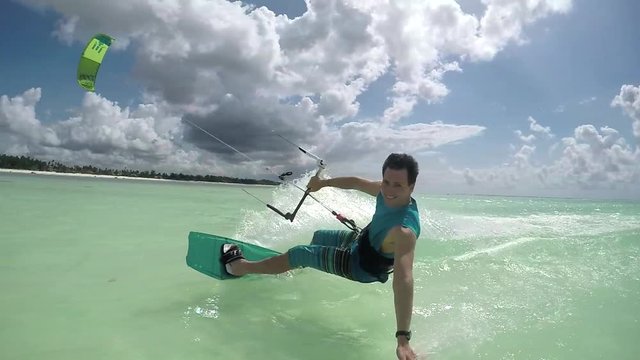 SLOW MOTION: Happy kite surfer kiteboarding and doing hand drag splashing water