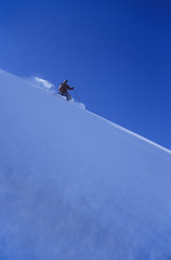Naklejka na ściany i meble Side view of a person skiing down slope against clear blue sky