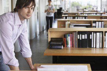 Portrait of a young male architect studying blueprint in office