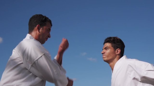 Young people, athletes, sport activity, combat and extreme sports, hispanic men practice in karate and traditional martial arts. Simulation of fight on the beach near the sea