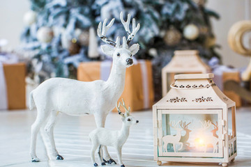 closeup christmas figurine of deer and fawn standing near nightlight on the background of the...
