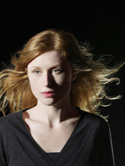 Closeup of beautiful woman with windswept hair looking away on black background