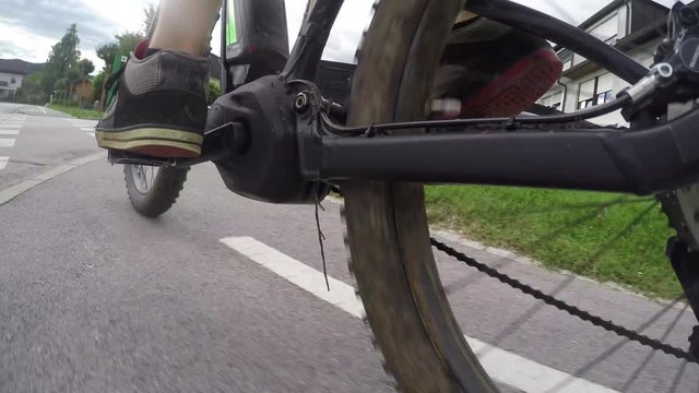 CLOSE UP: Unrecognizable man riding electric bicycle on cycling path in suburbs