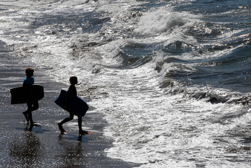 Two young boys entering the sea with boogie surf tables