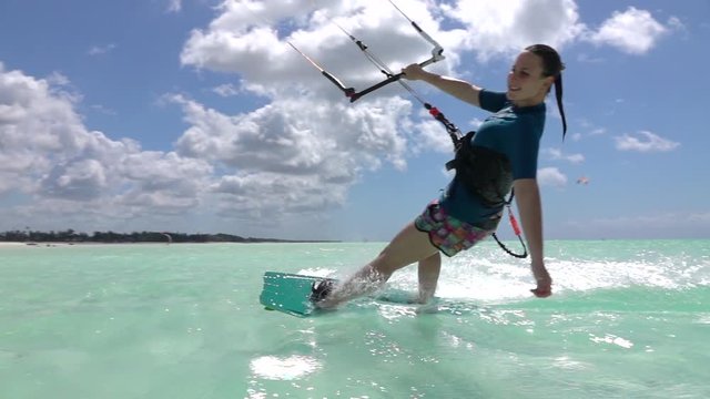 SLOW MOTION:  Happy young surfer girl kiteboarding in perfect blue ocean
