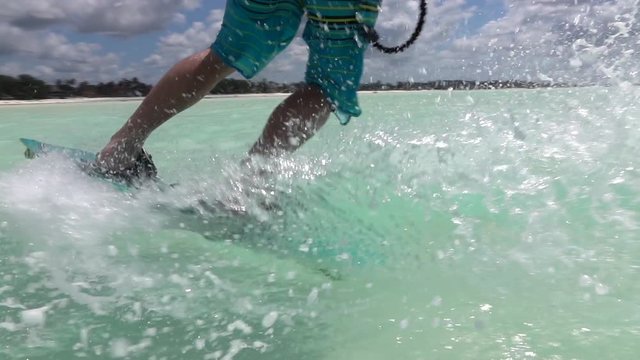 SLOW MOTION CLOSE UP: Young kite surfer kiteboarding and splashing sea water