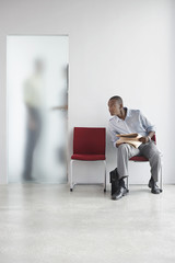 Young man listening to two people talk behind translucent door in office