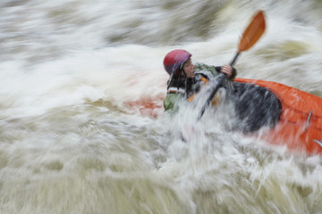 Side view of a blurred woman kayaking in rough river