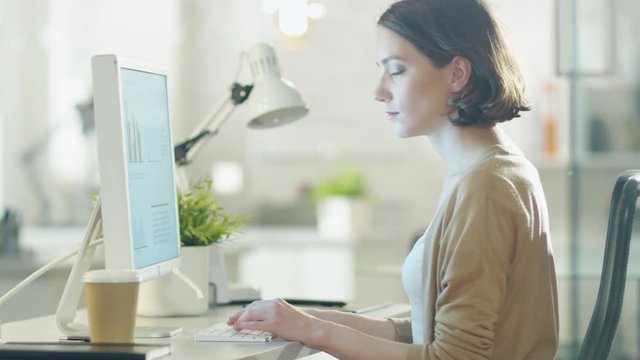 Young Beautiful Woman Works at Her Desktop Computer. Sitting in Her Light and Modern Office.  Shot on RED Cinema Camera in 4K (UHD).