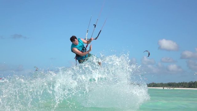 SLOW MOTION: Young kite surfer has fun jumping tricks in tropical ocean